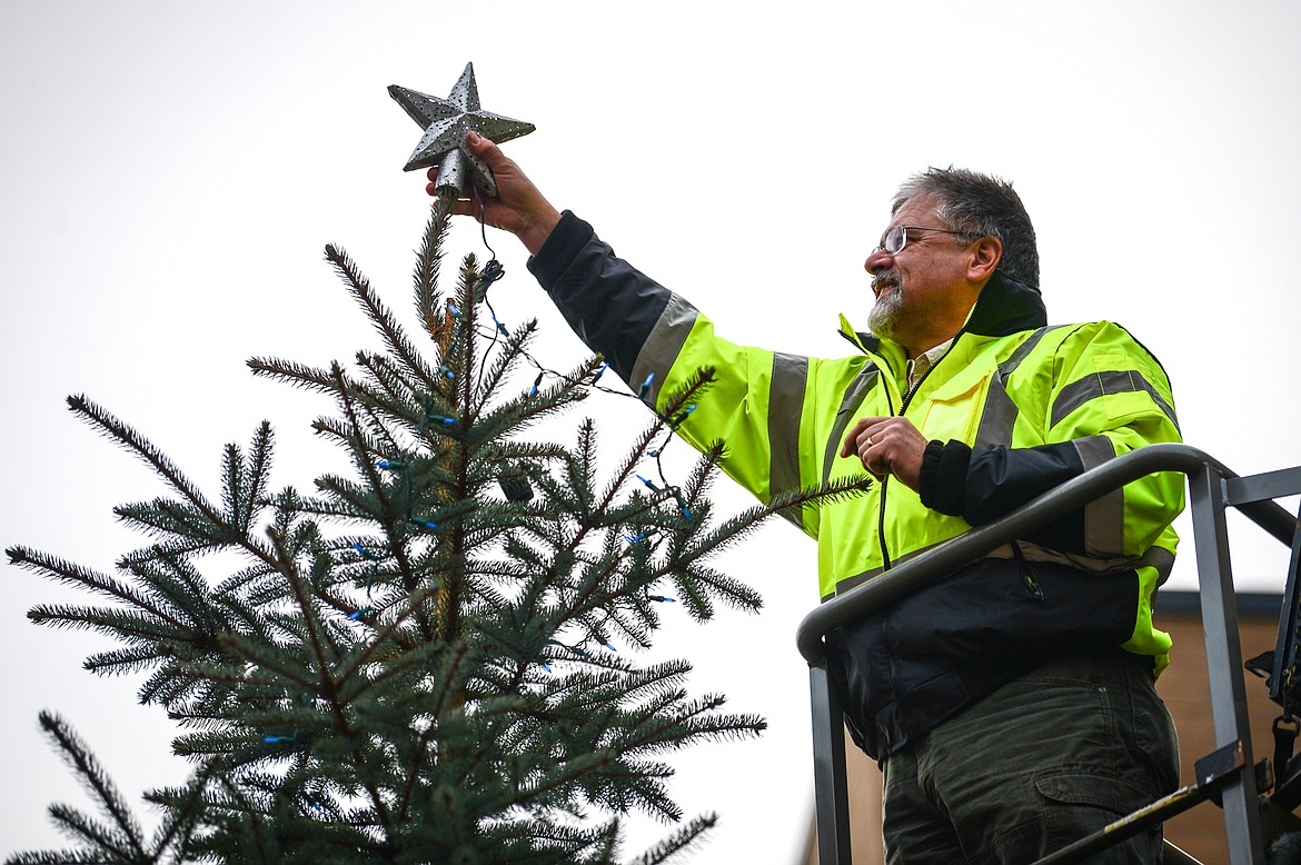 David Covill, building maintenance manager for Flathead County, places a star on top of a tree decorated with blue Christmas lights to commemorate law enforcement officers killed in the line of duty outside the Flathead County Justice Center on Tuesday, Dec. 8. (Casey Kreider/Daily Inter Lake)