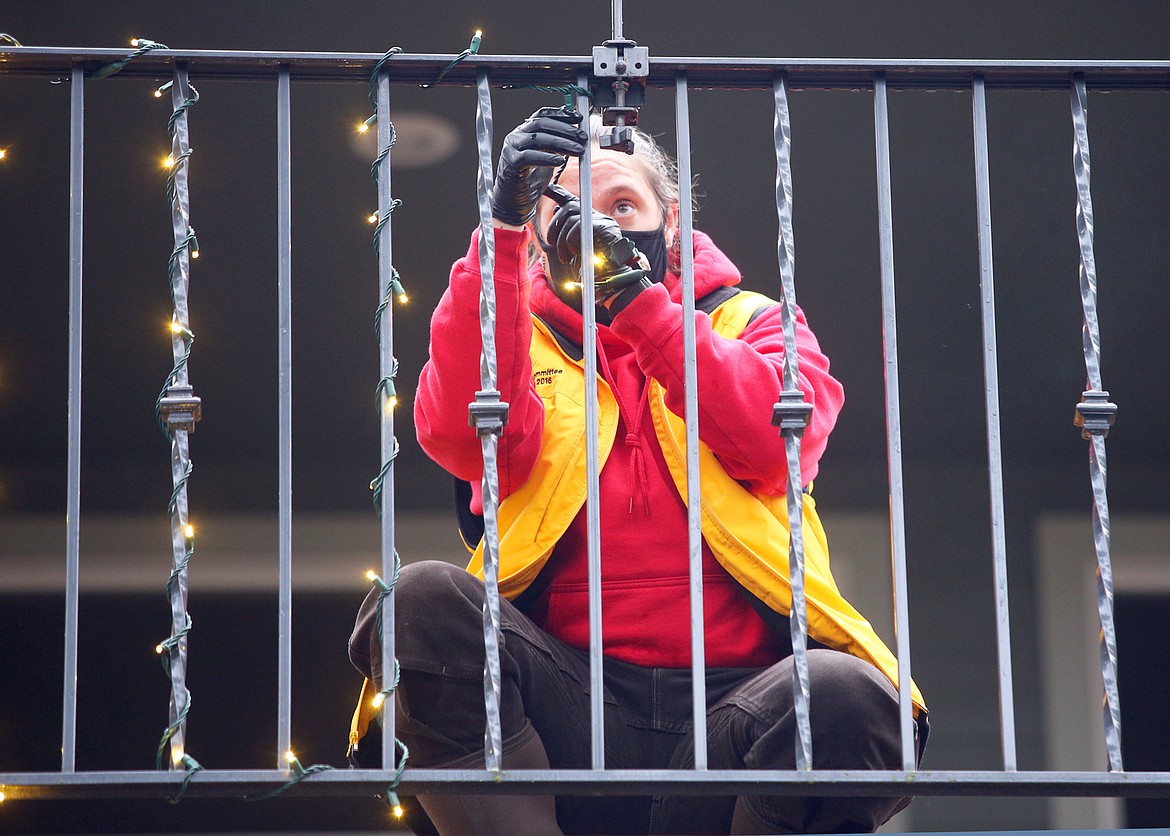 Bailey Reichenberg attaches Christmas lights to the railing outside the home of Ron and Judi Isaac on Wednesday.