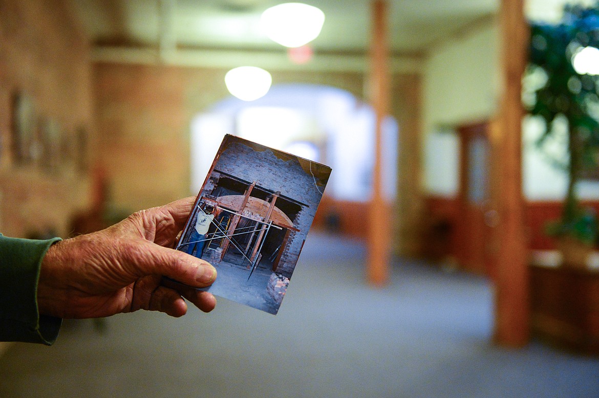 Bill Goodman displays an old photo of the construction of a brick archway on the second floor of the KM Building in Kalispell on Friday, Dec. 4. (Casey Kreider/Daily Inter Lake)