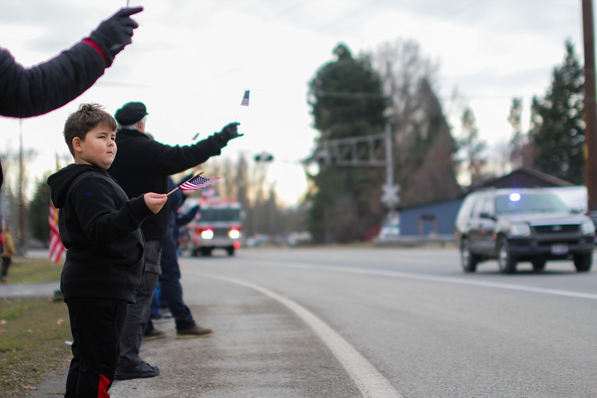 Seven-year-old Brandon Chapman stands next to Highway 200 with his mother, Cayla Magana, watching the procession of first responders. Magana said she did not know Victorino personally, but her mom did. “I wanted to teach my boy,” she said.