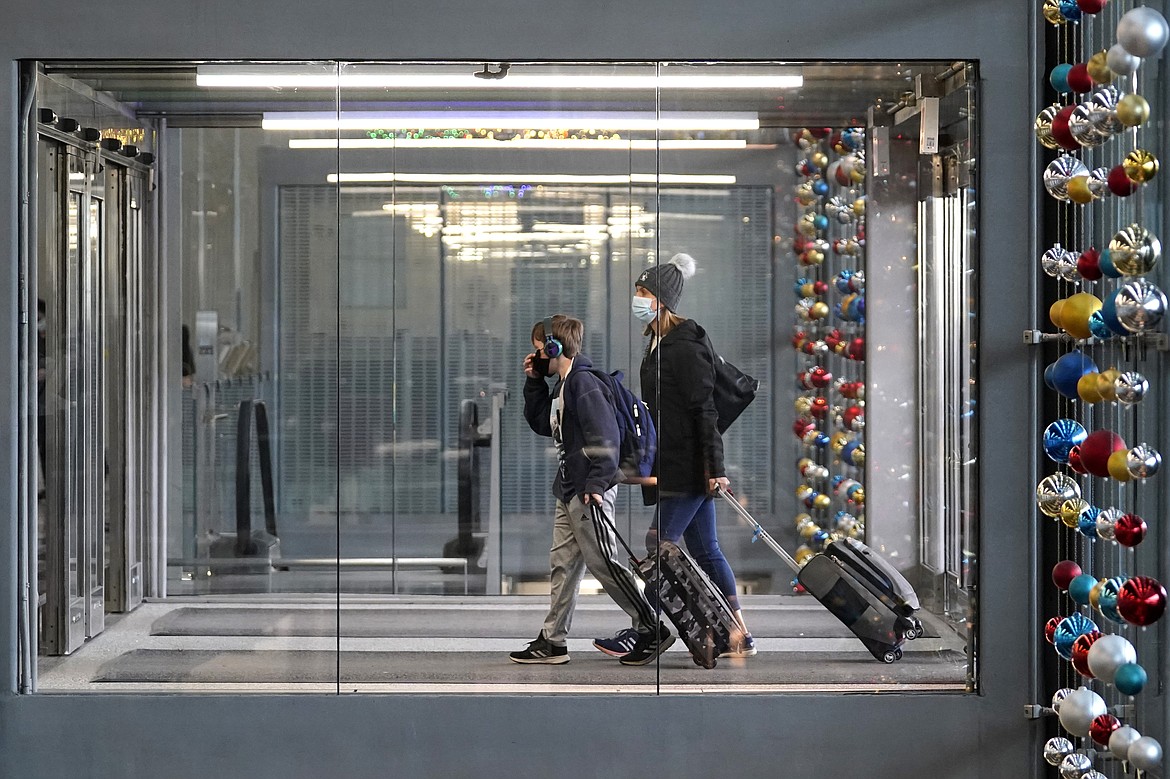 In this Nov. 29, 2020, file photo, travelers walk through Terminal 3 at O'Hare International Airport in Chicago. With some Americans now paying the price for what they did over Thanksgiving, health officials are warning people — begging them, even — not to make the same mistake during the Christmas and New Year's season.