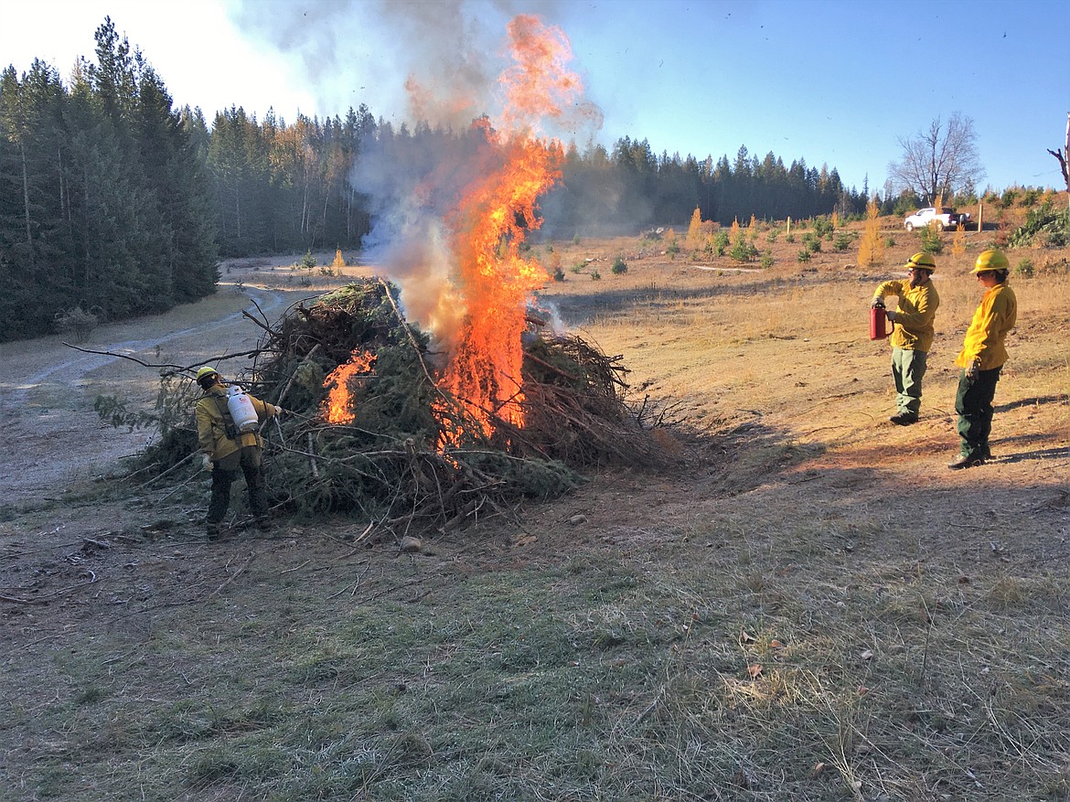 Staff from the Natural Resources Department of the Kalispel Tribe burn slash piles in the meadow.