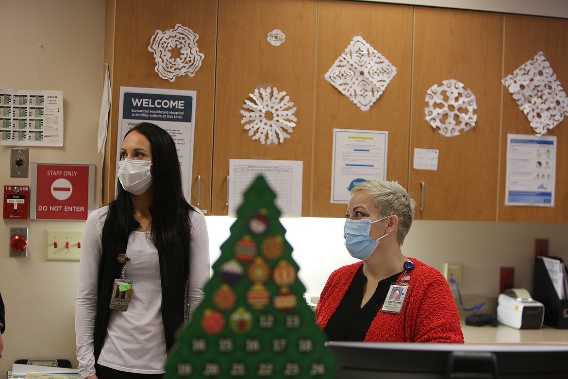 Julie Nishida, nurse and house supervisor at Samaritan Hospital, left, and Dr. Andrea Carter, Chief Medical Officer, chat momentarily with other healthcare workers behind the central desk in the hospital's intensive care unit.