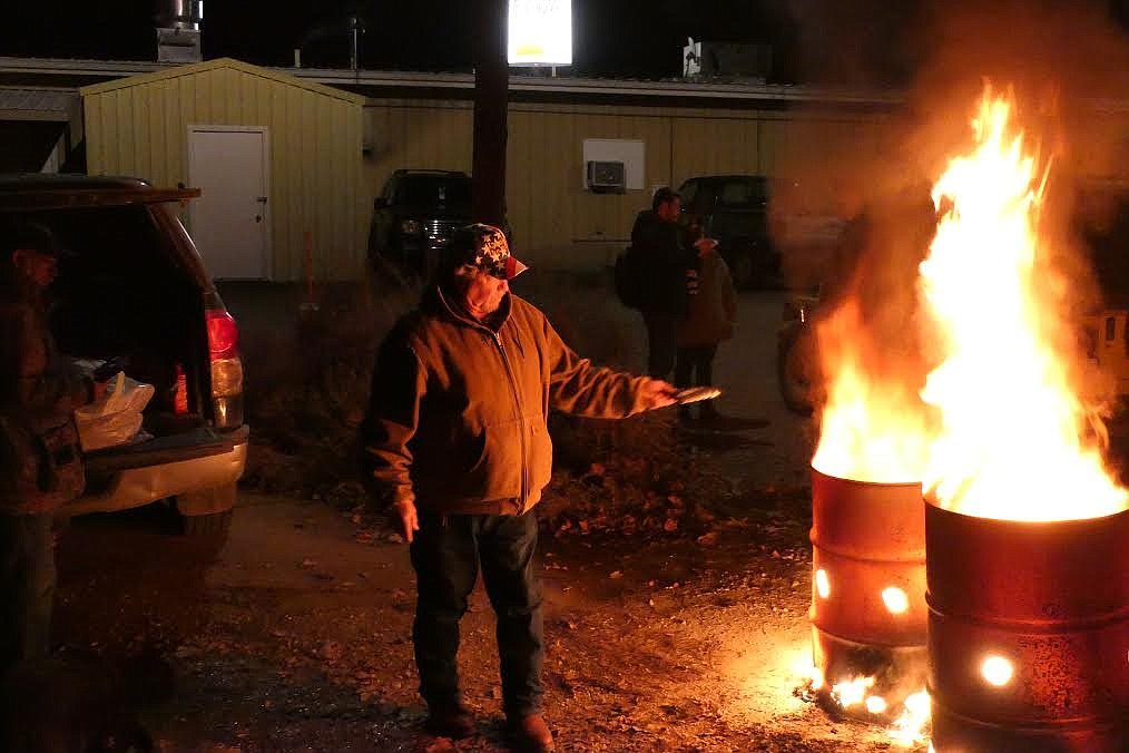 U.S. Army veteran Dan Johnson puts a flag in one of the burn barrels in the parking lot behind the Horse Plains VFW during a recent flag retirement ceremony. (Chuck Bandel/Valley Press)