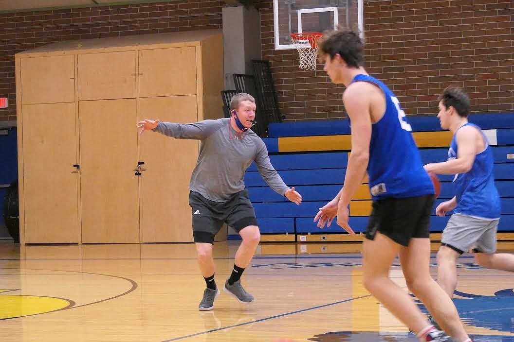 Thompson Falls boys basketball coach Jake Mickelson (gray shirt) demonstrates technique with Plains transfer Kade Pardee (blue jersey). (Chuck Bandel/Valley Press)