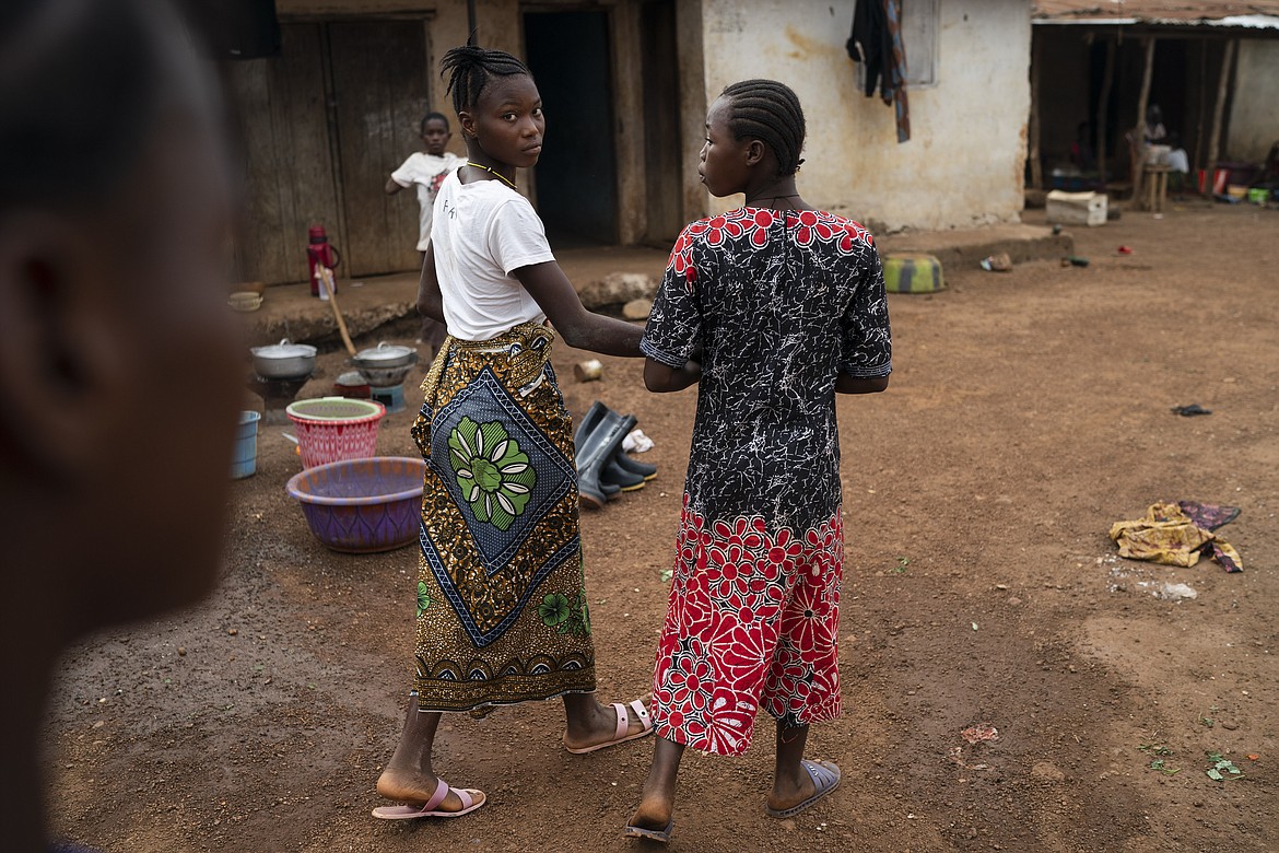 Marie walks with a friend on a street in Komao village, on the outskirts of Koidu, district of Kono, Sierra Leone, Sunday, Nov. 22, 2020. A man, in his mid-20s, first caught a glimpse of Marie as she ran with her friends past his house near the village primary school. Soon after, he proposed to the fifth-grader. “I’m going to school now. I don’t want to get married and stay in the house,” she told him. But the pressures of a global pandemic on this remote corner of Sierra Leone were greater than the wishes of a schoolgirl.