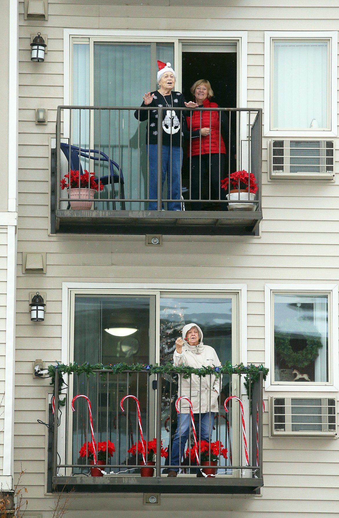 Affinity at Coeur d'Alene residents come out on their balconies to join a Christmas sing-along on Tuesday.