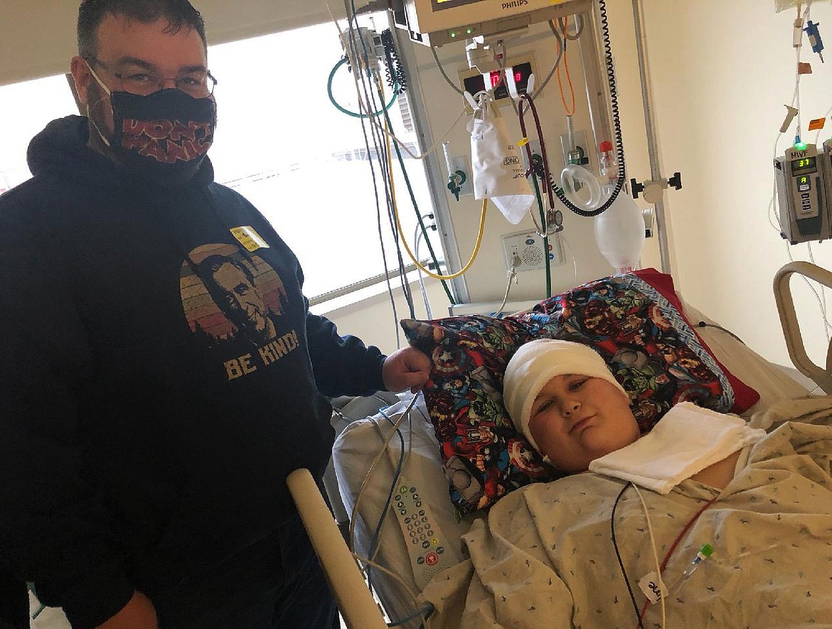 Jacob Markham, 14, is seen here with his dad, Ben Markham, on Dec. 4, one day after undergoing brain surgery at Sacred Heart Children’s Hospital to remove a large mass in his brain. He is now home with his mom, dad and sister Ellie.