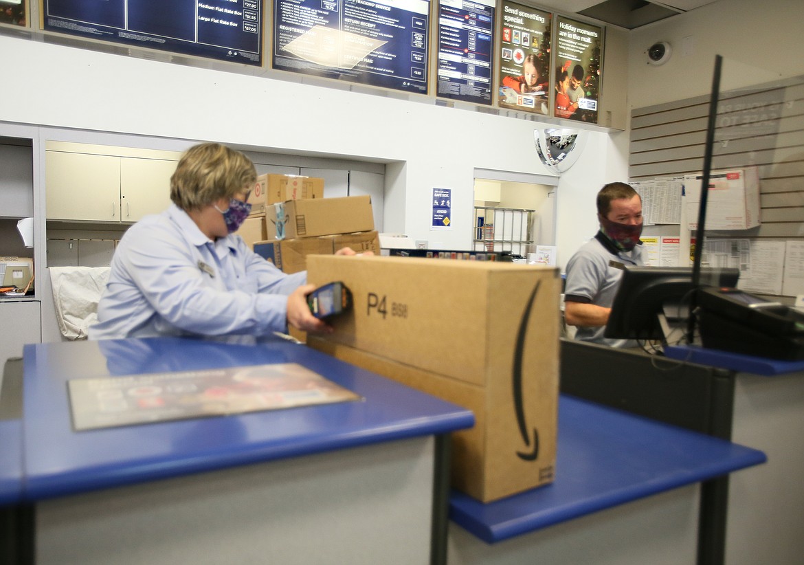 U.S. Postal Service workers process packages Tuesday in the downtown Coeur d'Alene post office. Because of the pandemic and historic amounts of mail going out, customers should be aware of delays in shipping brought on by capacity challenges with airlifts and trucking for moving this volume of mail.