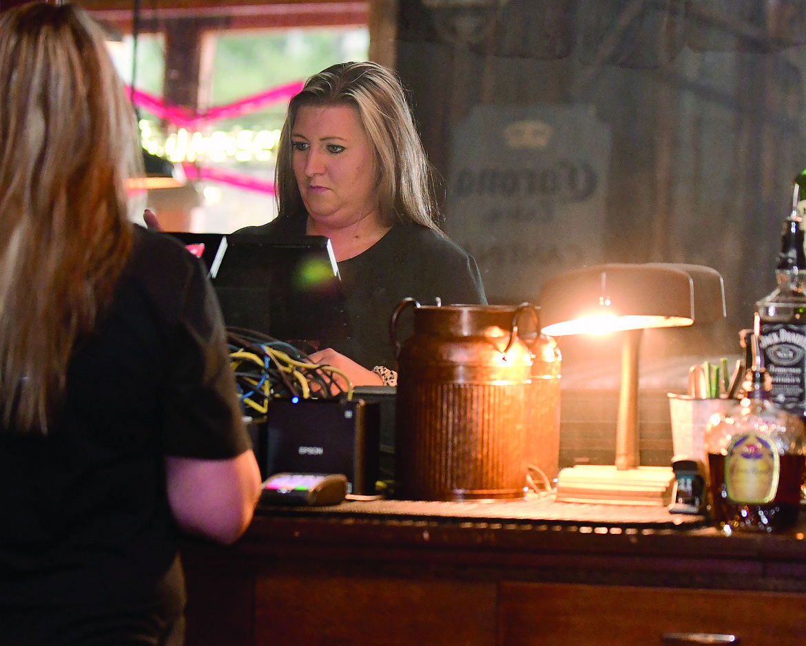 Amanda Walsh, who helps run the Paul Bunyan Bar and Grill with her father John VanValkenburg, works at the well-stocked and fully refurbished early 1900s-era back bar they installed before the business opened earlier this fall. (Teresa Byrd/Hungry Horse News)