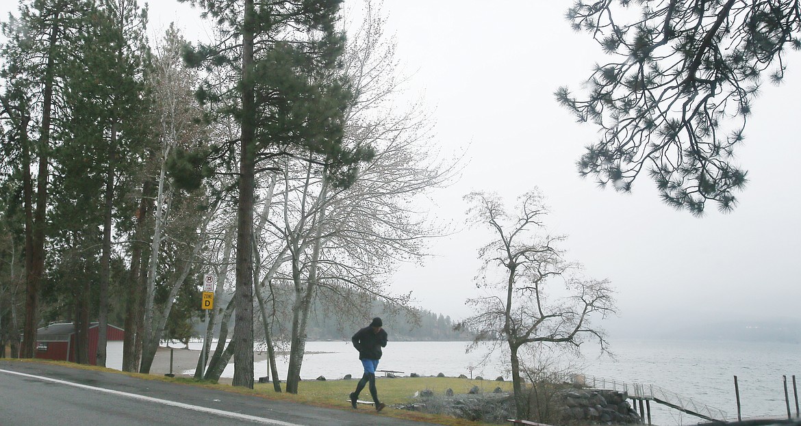 A jogger runs along the North Idaho Centennial Trail near the North Idaho College Beach as mist hovers above Lake Coeur d'Alene on a gray Thursday afternoon. Gray and rainy will be common this December, and a white Christmas is probably not going to happen. January, however, will be the snowy gift that keeps on giving.