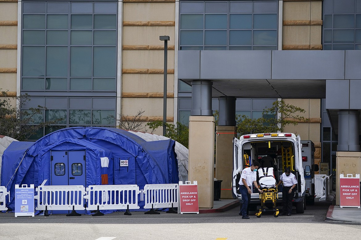 In this Dec. 16, 2020, file photo, Emergency Medical Services transfers a patient at the Los Angeles County + USC Medical Center hospital in Los Angeles. Hospitals across California have all but run out of intensive care beds for COVID-19 patients, ambulances are backing up outside emergency rooms, and tents for treating the sick are going up as the nation’s most populous state emerges as the latest epicenter of the U.S. outbreak.