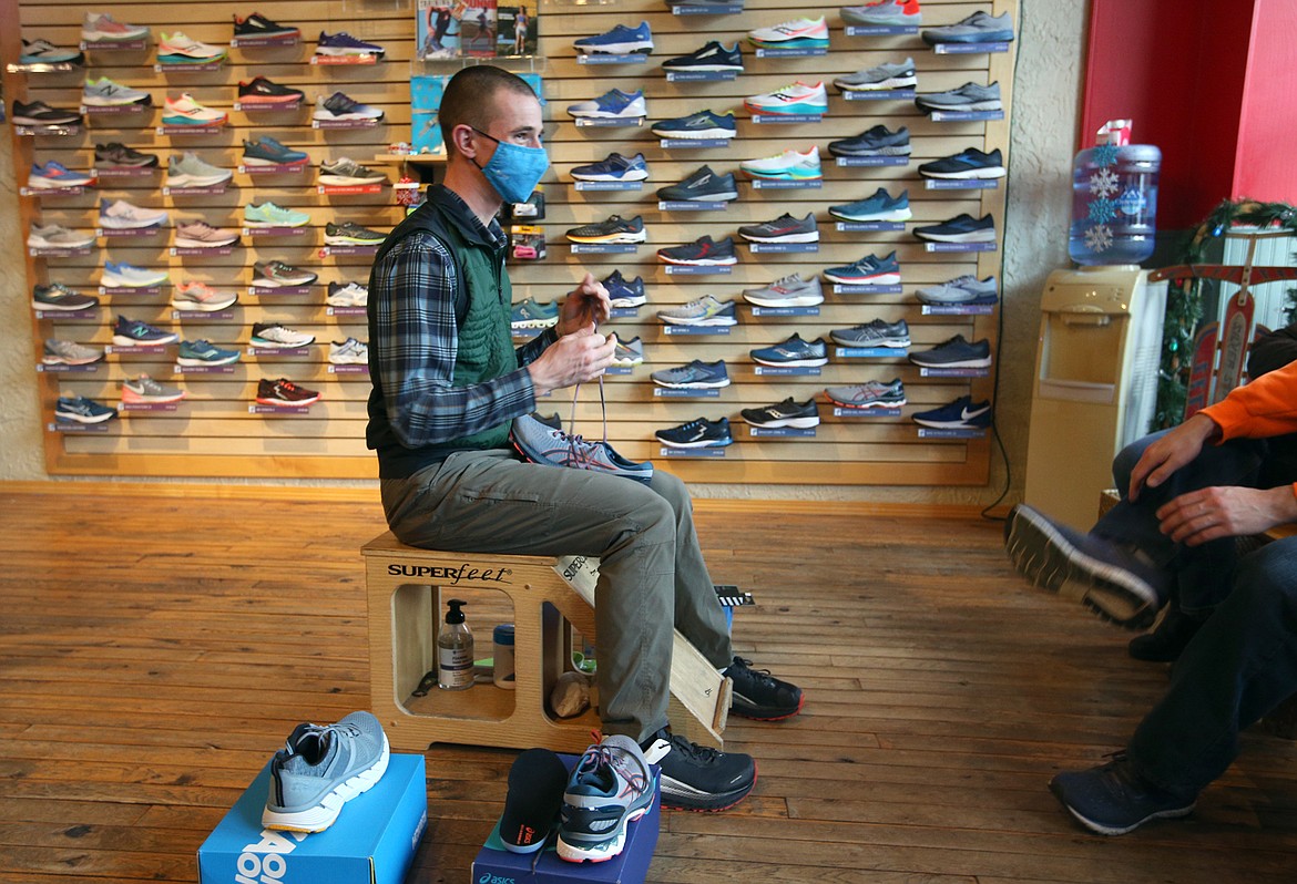 Wyatt Goshorn works with a customer who was trying on running shoes Thursday at Fleet Feet.