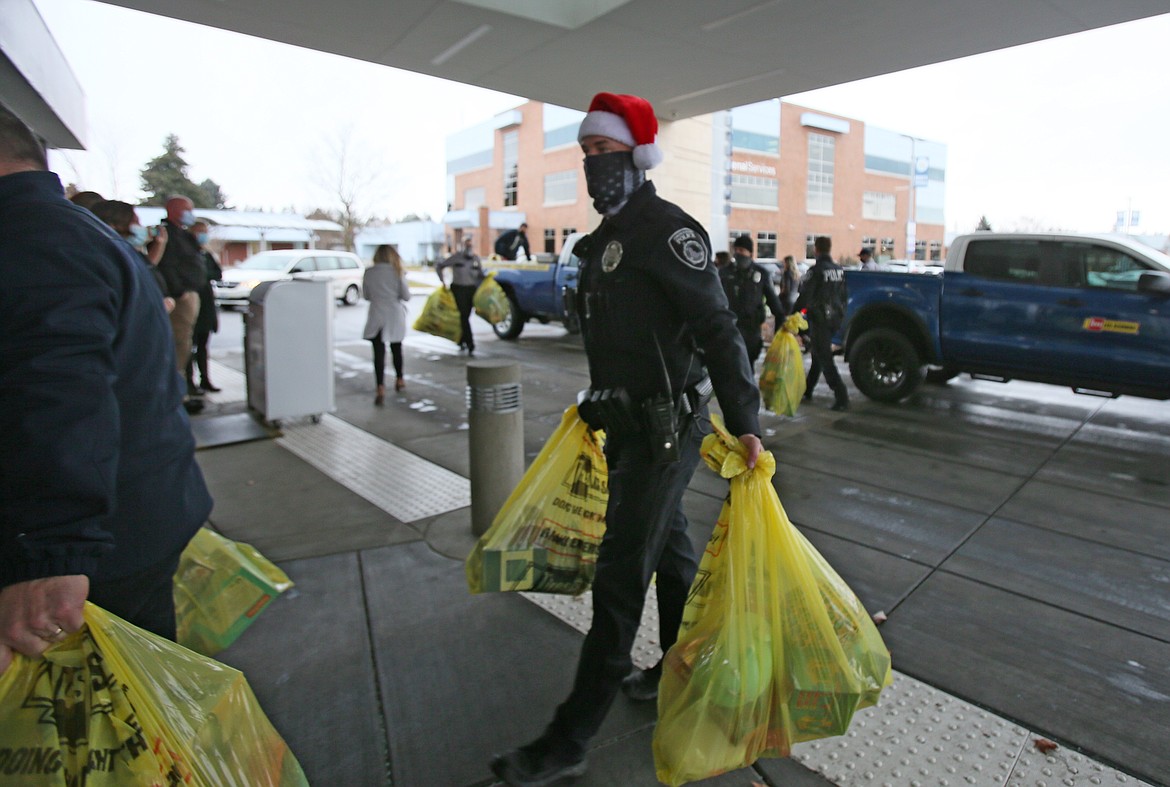 Coeur d'Alene Police Officer Eric Breakie spreads Christmas cheer on Friday as he helps carry bags of toys that will go to children and teens in the pediatric unit at Kootenai Health. About $5,000 in gifts were delivered as part of the Coeur d'Alene Police Foundation Children's Hospital Toy Drive.