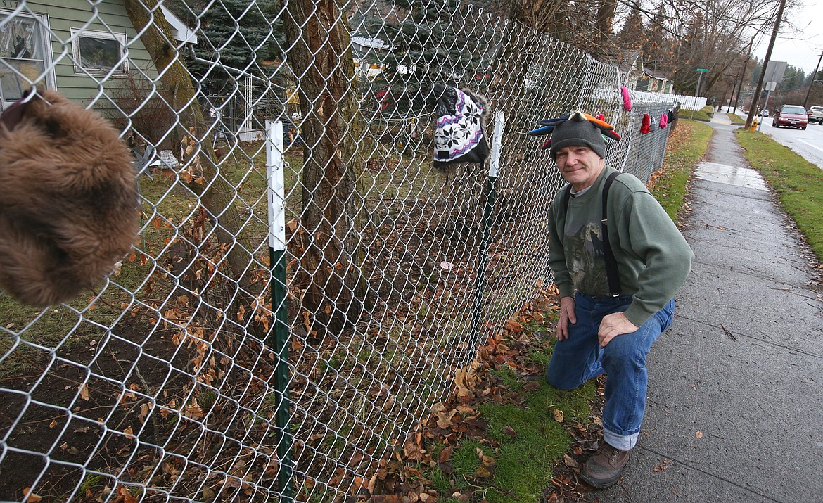 Pat Moore poses next to his fence on Harrison Avenue, where he hung free stocking caps on Thursday.