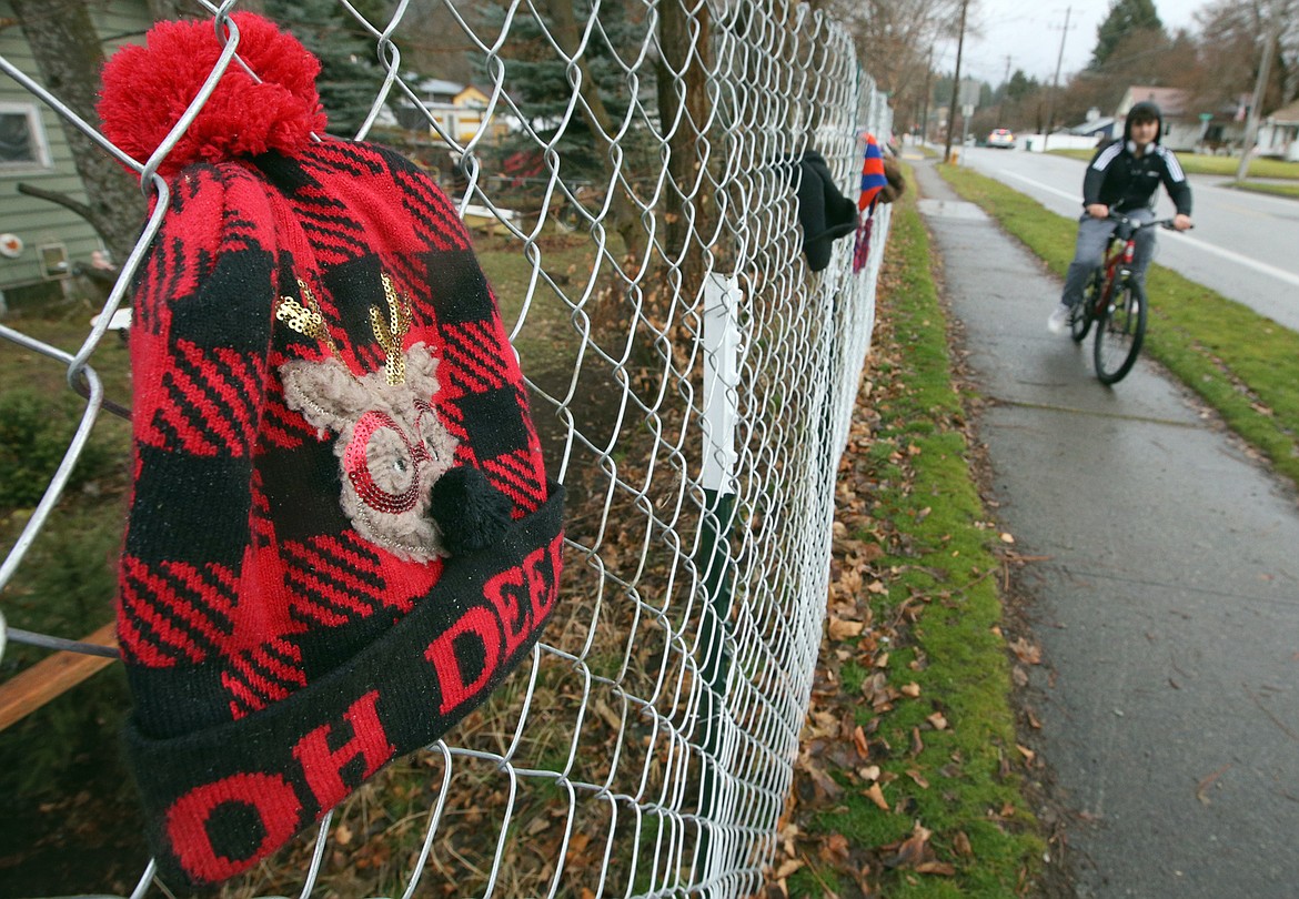 A young cyclist rides past the Harrison Avenue fence with free hats hanging from it on Thursday.