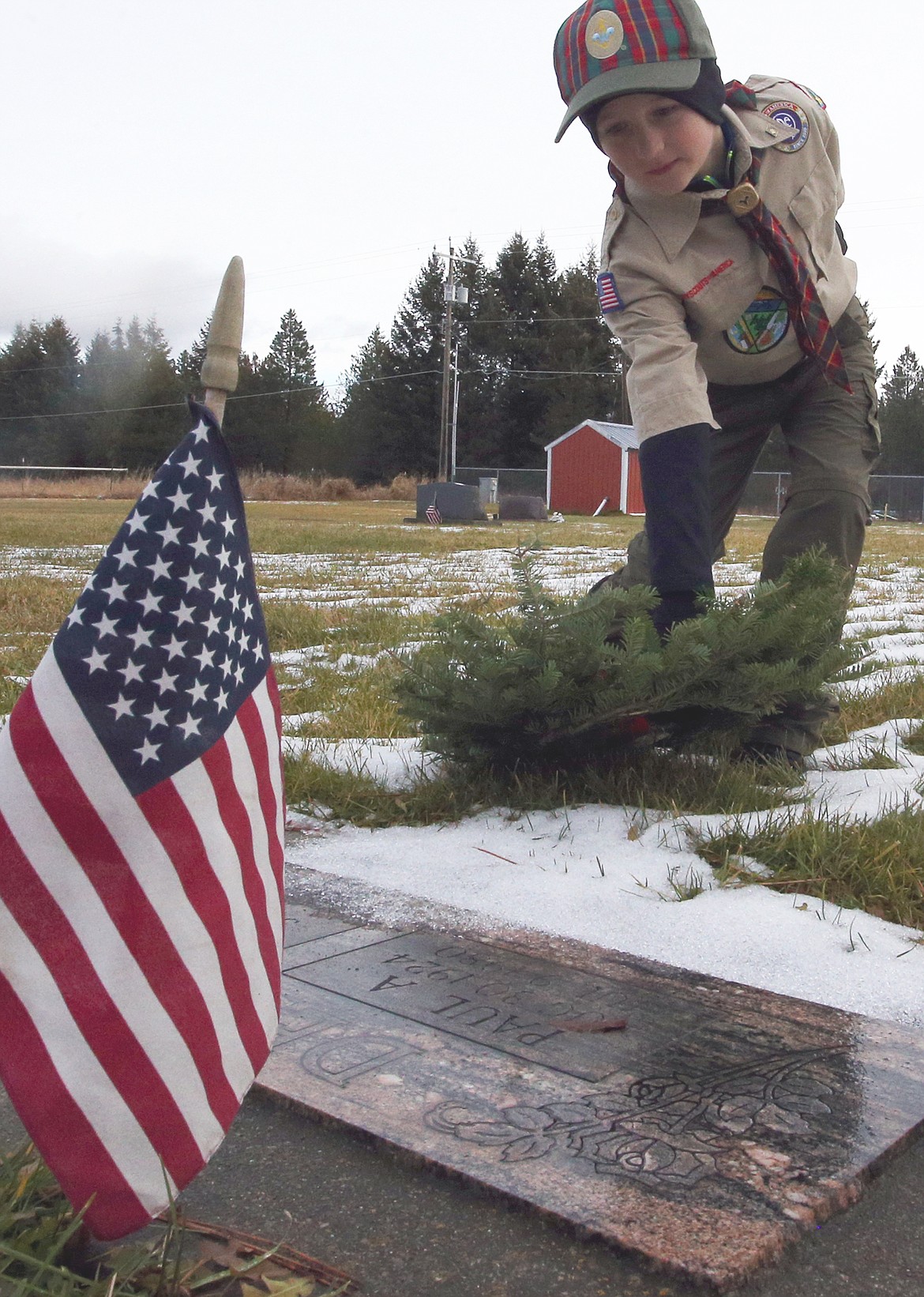 Michael Gallus places a wreath at a veteran's gravesite on Saturday at Pinegrove Cemetery.