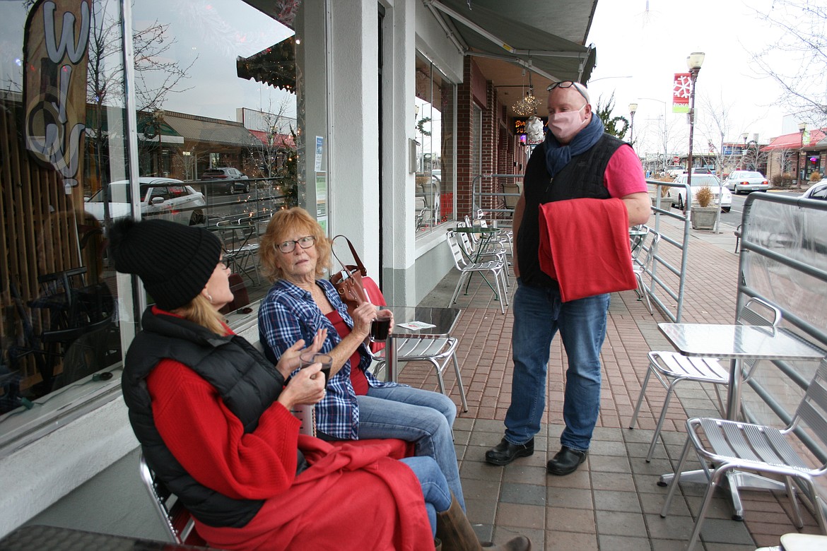 Roost owner Bruce Bailey (right) talks with customers Jill Hoovel (left) and Vicky Calker (center). Patio dining in December is one way Bailey has reinvented his business during the COVID-19 pandemic.