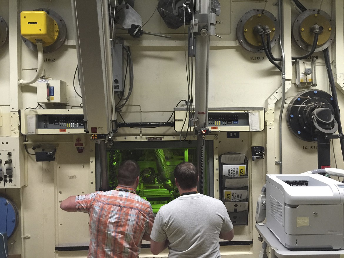 In this May 11, 2015, file photo, Colt Killian, left, and Rob Cox manipulate radioactive material remotely behind a protective barrier at the Hot Fuel Examination Facility at the Idaho National Laboratory near Idaho Falls, Idaho. Idaho is the top choice for the first new nuclear test reactor in the U.S. in decades. The U.S. Department of Energy on Monday, Dec. 21, 2020, released a draft environmental impact statement saying the Idaho National Laboratory is its preferred site for the proposed Versatile Test Reactor.