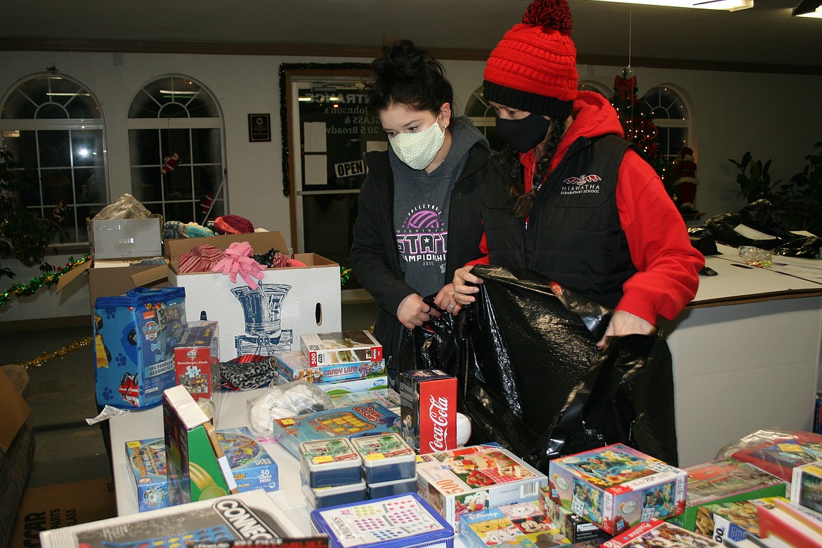 Alexandra Monroy (back) and Lena Jenson peruse the selection of toys while assembling toy bags for the Othello Christmas basket project. Assembly was done the week of Dec. 14, and the baskets were distributed Dec. 19.