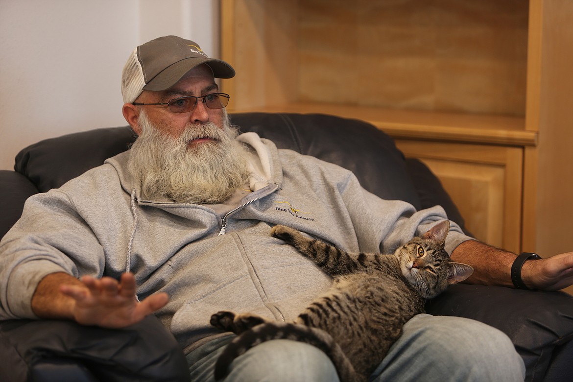 Rod Richeson, owner of Blue Sky Aviation, sits and talks with a customer while his staff member, Rudder, cuddles up in his lap.