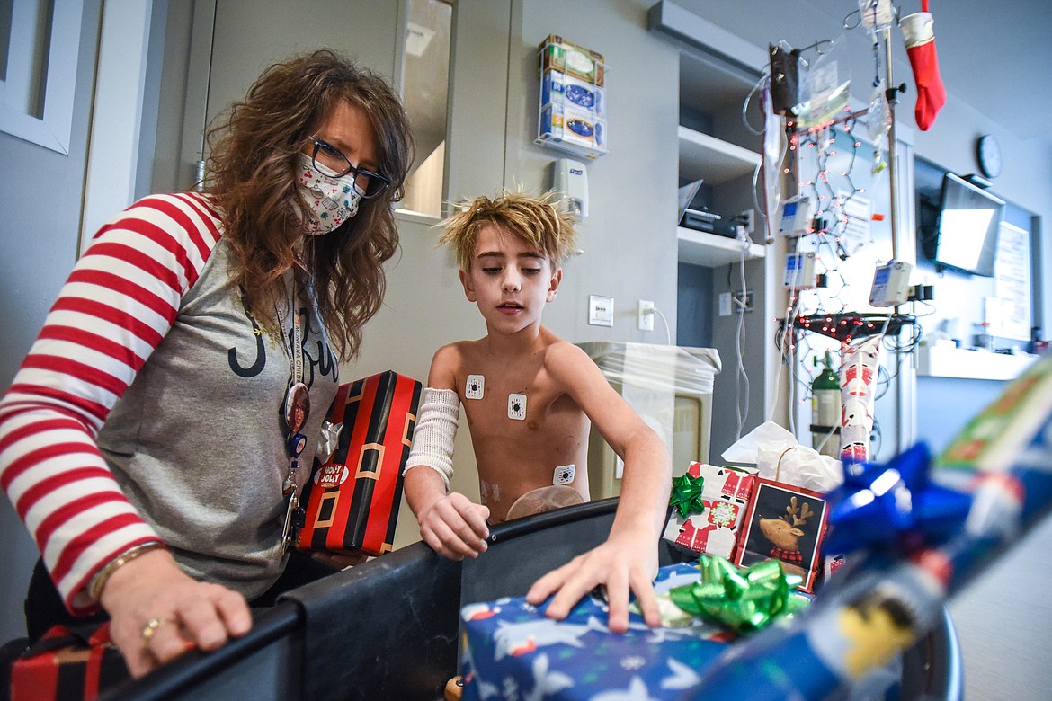 Coleman Lee, right, a patient in the pediatric wing at Montana Children's, looks through gifts for himself and his family with Amy Rohyans Stewart, Child Life Specialist and Coordinator with the hospital, on Wednesday, Dec. 23. Montana Children's is providing gifts to patients and their families through their Virtual Toy Drive during the holidays. (Casey Kreider/Daily Inter Lake)