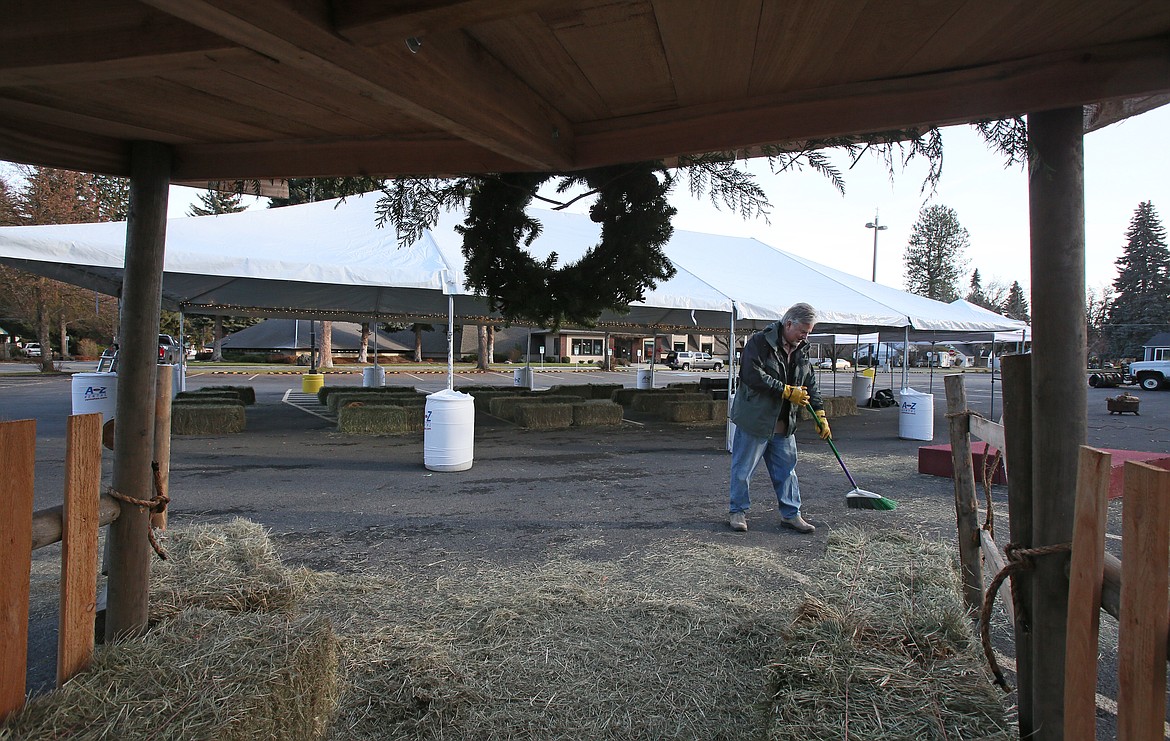 Mike Haas, executive director of ministries at Christ the King Lutheran Church in Coeur d'Alene, sweeps hay by a stable in the parking lot Wednesday as he and his team prepare for live outdoor Christmas Eve services starting at 11 a.m. today. "All are welcome, and it's open to anyone," Haas said.