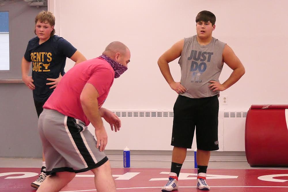 Clark Fork wrestling coach Charlie Crabb (red) goes over moves with sophomore 230-pounder Chandon Vulles. (Chuck Bandel/Valley Press)