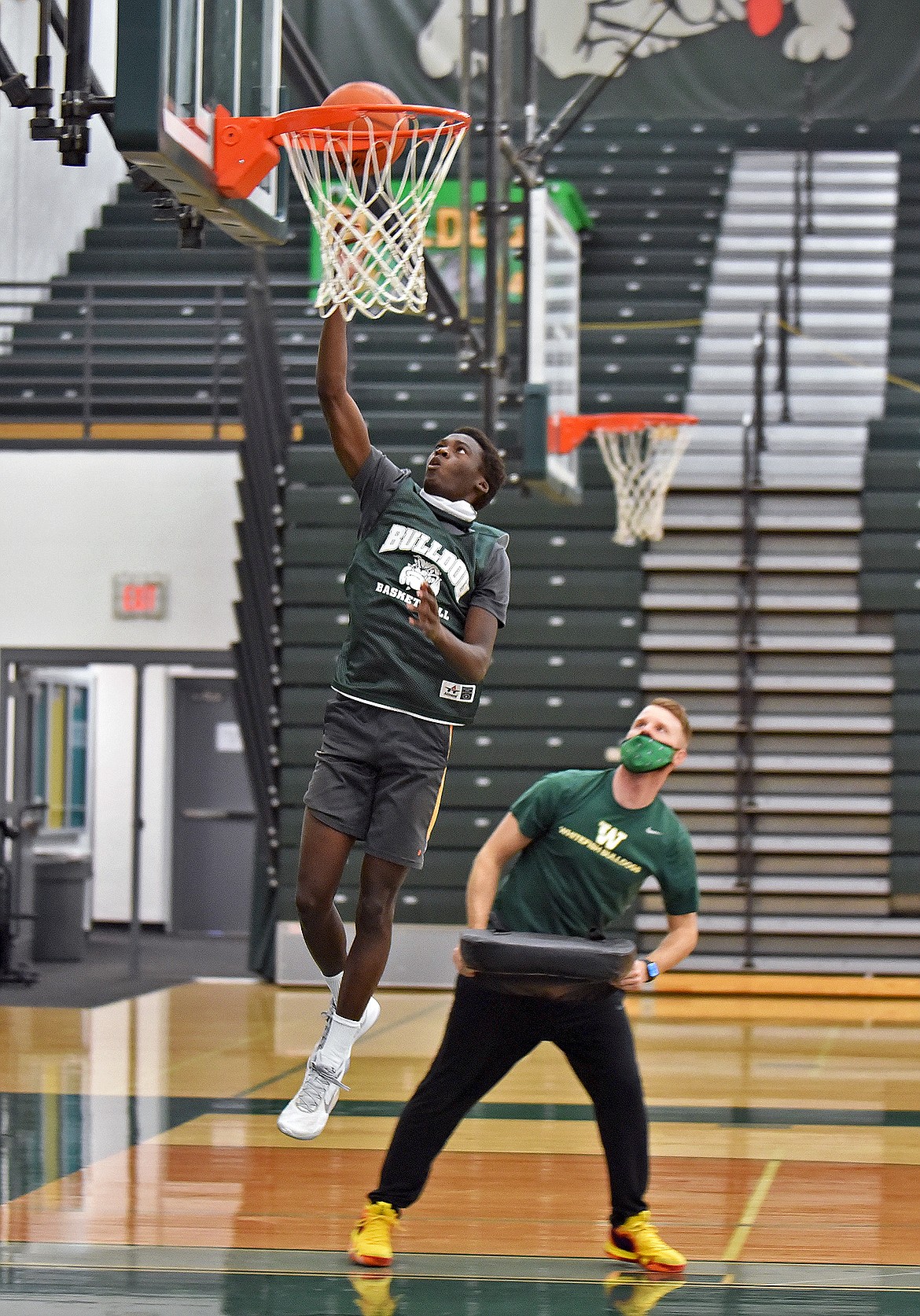 Bulldog Marvin Kimera lays the ball up toward the hoop during a drill at the Whitefish boys basketball practice Dec. 9. (Whitney England/Whitefish Pilot)