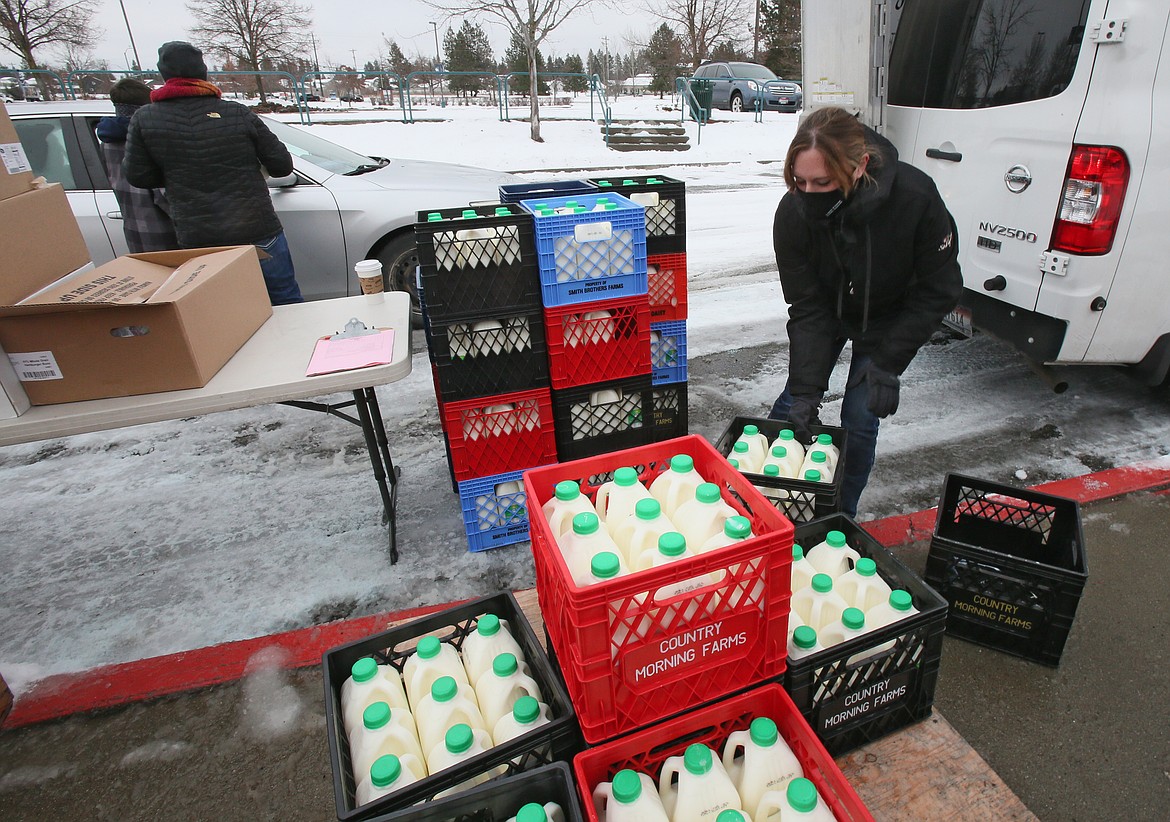 Coeur d'Alene School District Nutrition Services area manager Kelsey Blair arranges crates of half-gallon jugs of milk Monday at Lake City High School as she helps distribute five-day meal kits to local families.