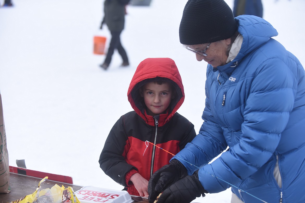 Grandma Ann Slayton, of Columbia Falls, helps her grandson, 6-year-old Clayton Kiel, make S'mores at the 50th annual Kalispell Sunriser Lions Club fishing derby. (Scott Shindledecker/Daily Inter Lake)