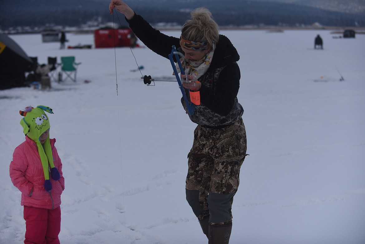 Kassie Fisher, of Kalispell, shows her daughter, 5-year-old Tenley, how to bait a hook during last Saturday's 50th annual Kalispell Sunriser Lions Club fishing derby. (Scott Shindledecker/Daily Inter Lake)