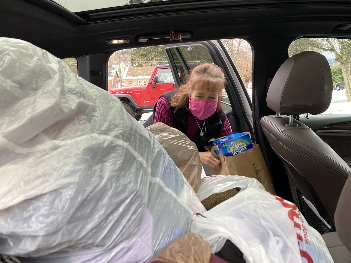 Family Promise of North Idaho Executive Director Cindy Wood helps unpack one of the two cars stuffed with donations from Beyond Bones Chiropractic Tuesday afternoon. (MADISON HARDY/Press)