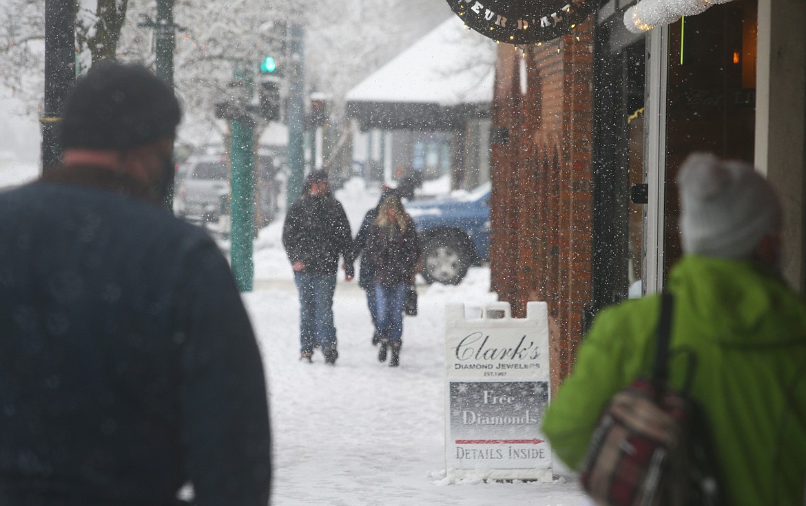 Snow falls as shoppers walk on Sherman Avenue Wednesday afternoon.