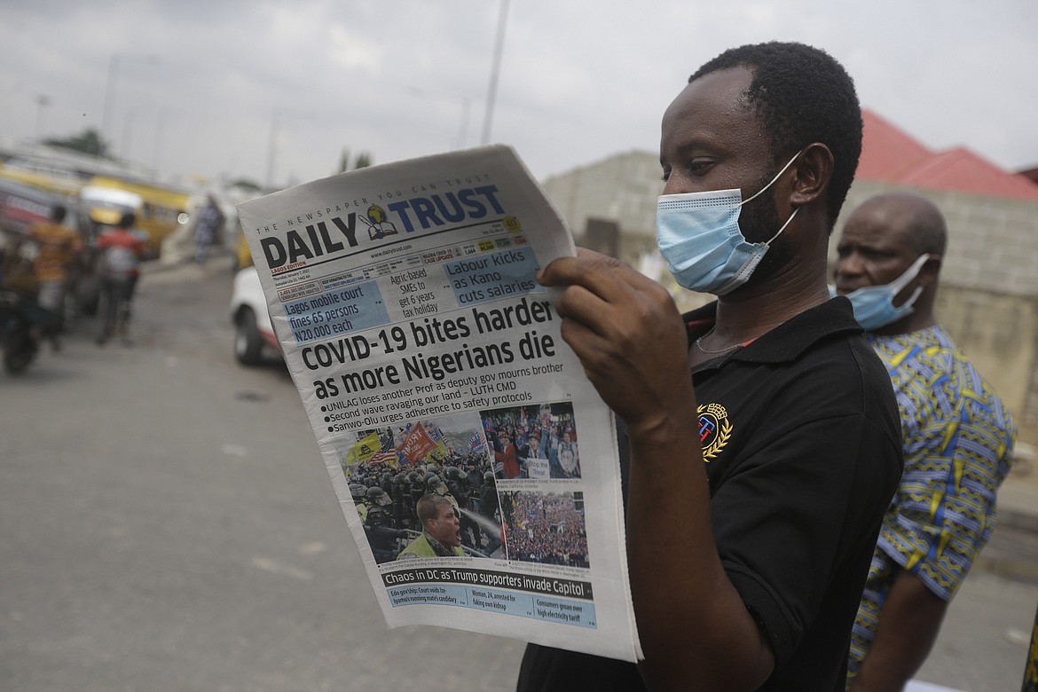 A man reads a newspaper reacting to the news of the assault on U.S Congress, on a street in Lagos, Nigeria, Thursday Jan. 7, 2021. News reports show police with gun drawn as protesters try to break into the House Chamber at the U.S. Capitol on Wednesday, Jan. 6, in Washington, USA.