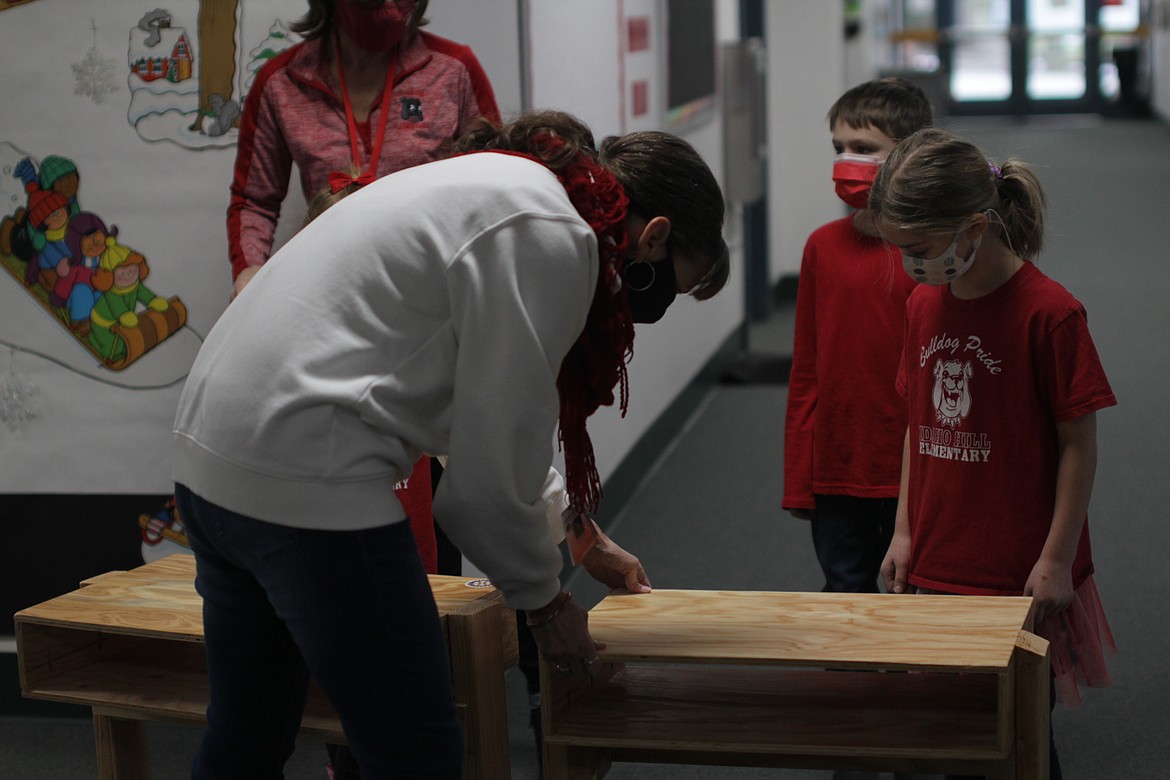 Principal Susie Luckey sets up desks for photos as second-grader Keith Campbell and first-grader Abigail Floyd watch Friday morning at Idaho Hill Elementary.