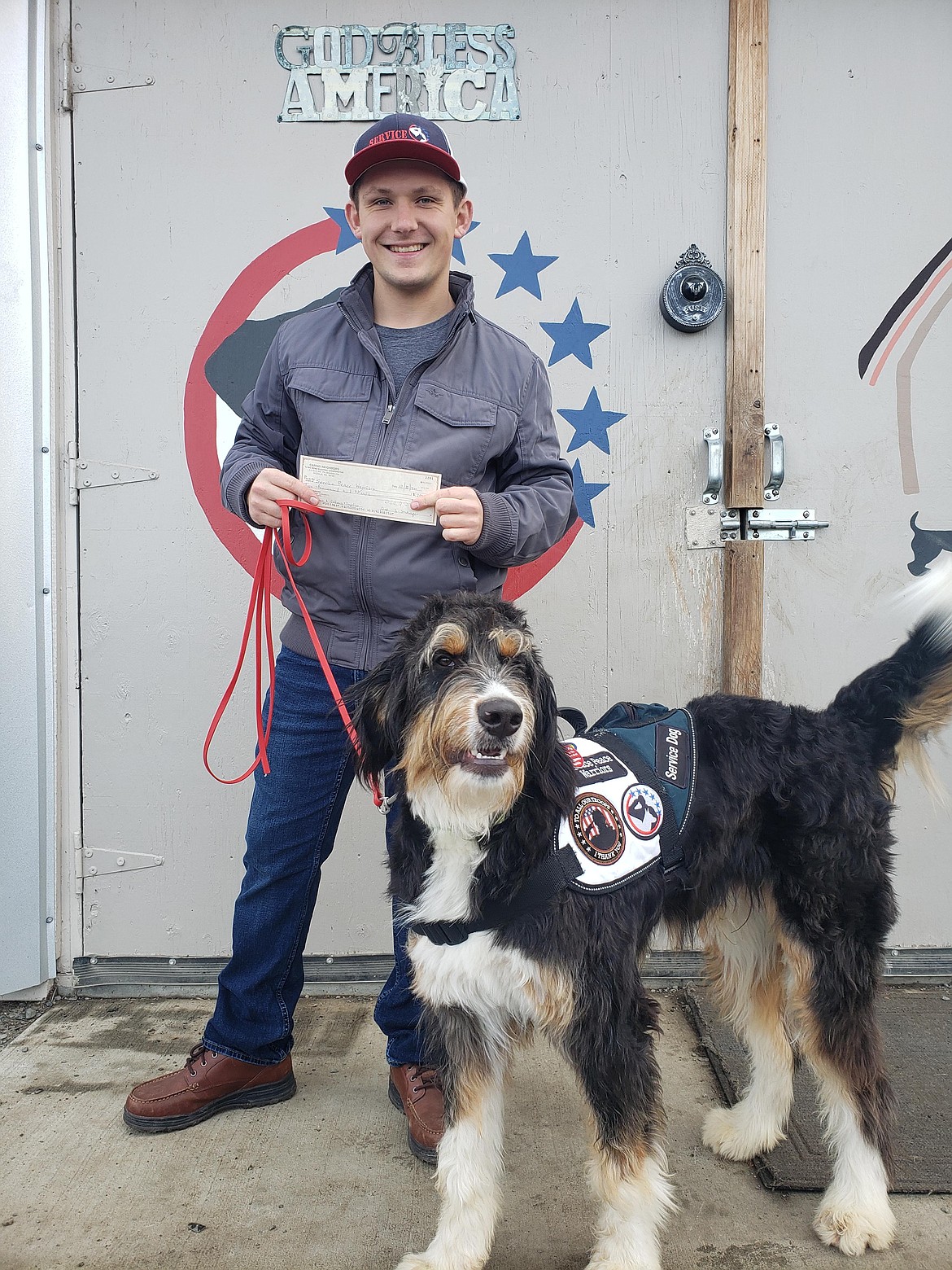 Chance Mattox of Service Peace Warriors and service dog Finn accept a donation from the Big Bend Electric Cooperative's Caring Neighbors program.