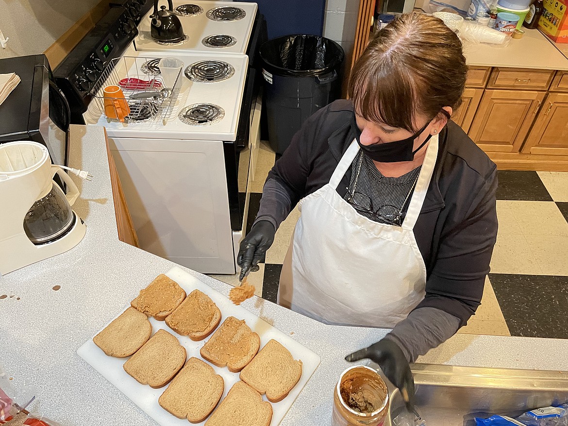 Michelle Boetger spreads peanut butter on slices of bread as she helps make 120 sandwiches for the homeless, something she has done every week since early 2017.