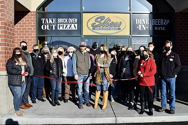 Slices Brick Oven House owner Bailey Jasper, flanked by family and members of the Moses Lake Chamber of Commerce, cuts the ribbon on her newly rebranded business Wednesday. Jasper decided to rechristen her business because the former owners were Italian, and she is not, and she "didn't want to pretend" to be something she wasn't.