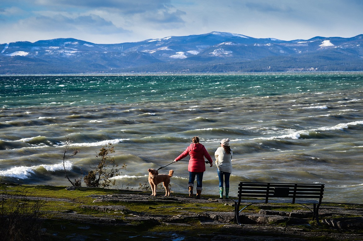 Beth Woods, left, and Shannon Amaral, with their dogs Murphy and Madison, take pictures of the waves rolling across Flathead Lake at Wayfarers State Park in Bigfork on Wednesday, Jan. 13. (Casey Kreider/Daily Inter Lake)