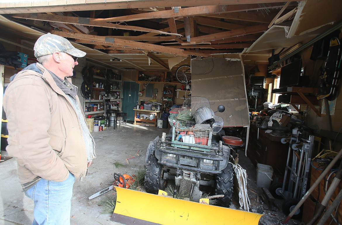 Mike Hohensee of Hayden on Thursday shows where a large piece of drywall crashed from his garage ceiling and knocked him off his bench when a tree landed on the roof during the windstorm Wednesday.