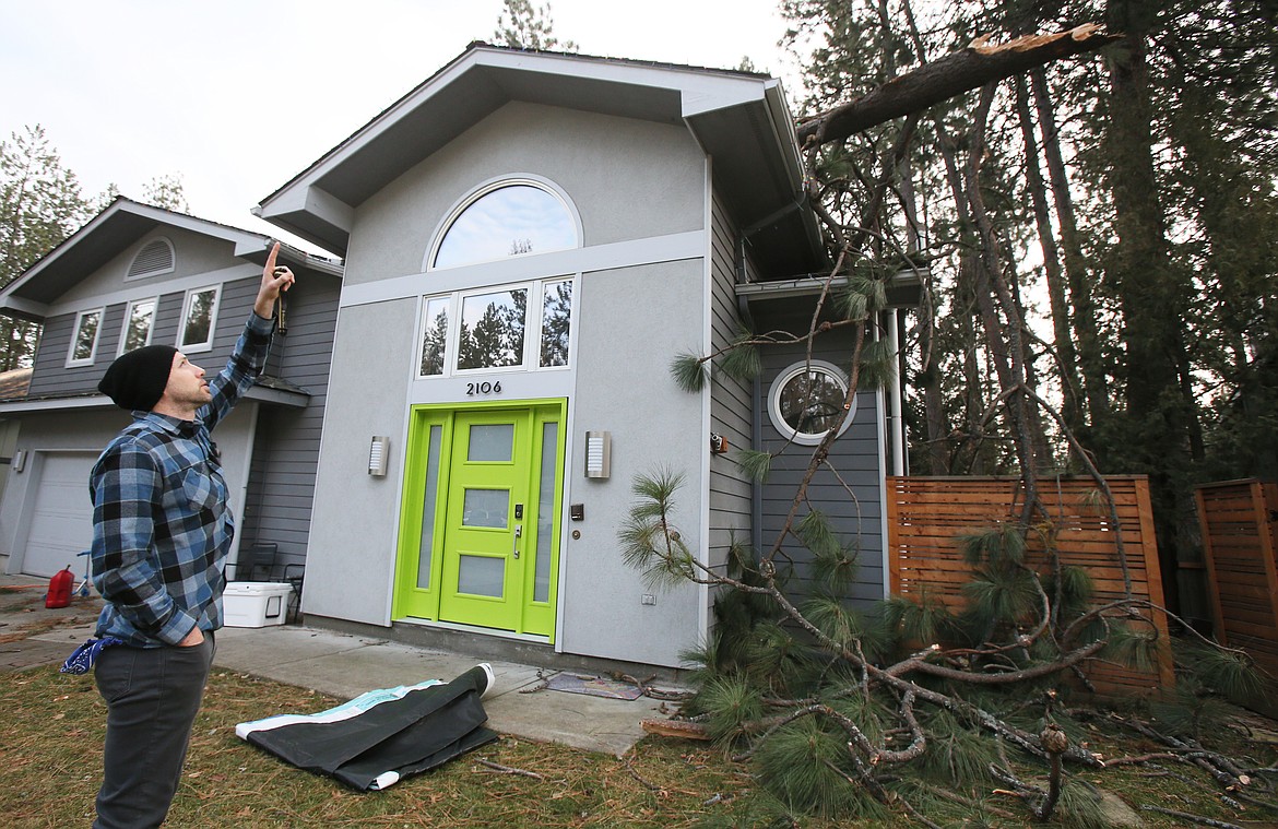 Charlie Miller on Thursday points up to where a piece of a forked-top tree split off during Wednesday's windstorm and landed on his roof, punching holes through the ceiling in some places. "It was a wild storm," he said.