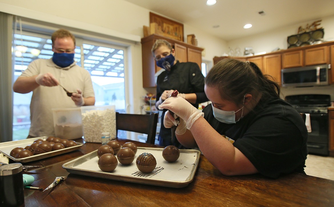 LoriAnn Macklin, 18, of Post Falls, drizzles chocolate on cocoa bombs during a visit to Village Bakery owner Dana Bellefeuille's house on Thursday. "I like to help make them," Macklin said.