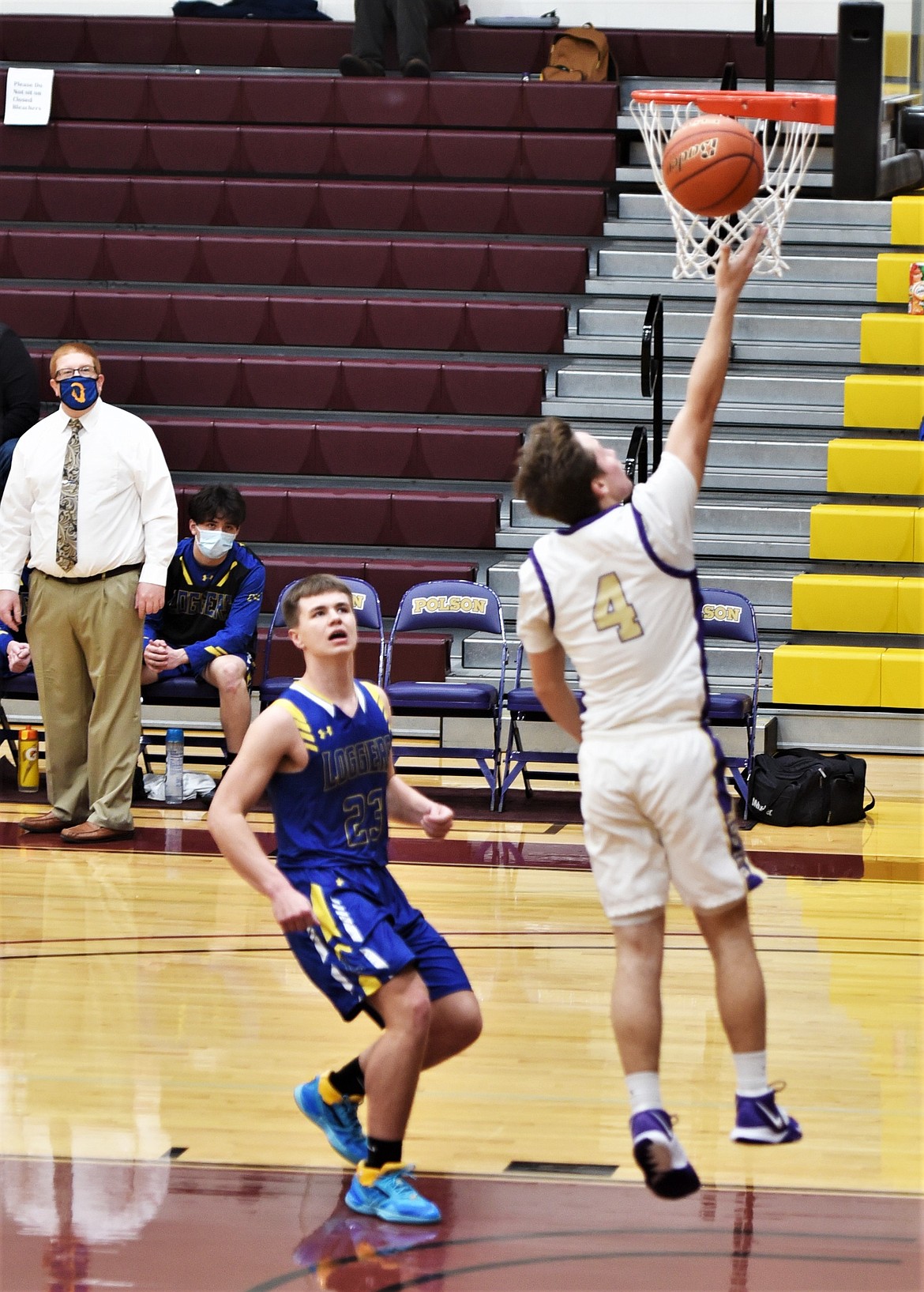 Polson's Xavier Fisher tosses a lay-up in front of Libby's Cy Stevenson. (Scot Heisel/Lake County Leader)