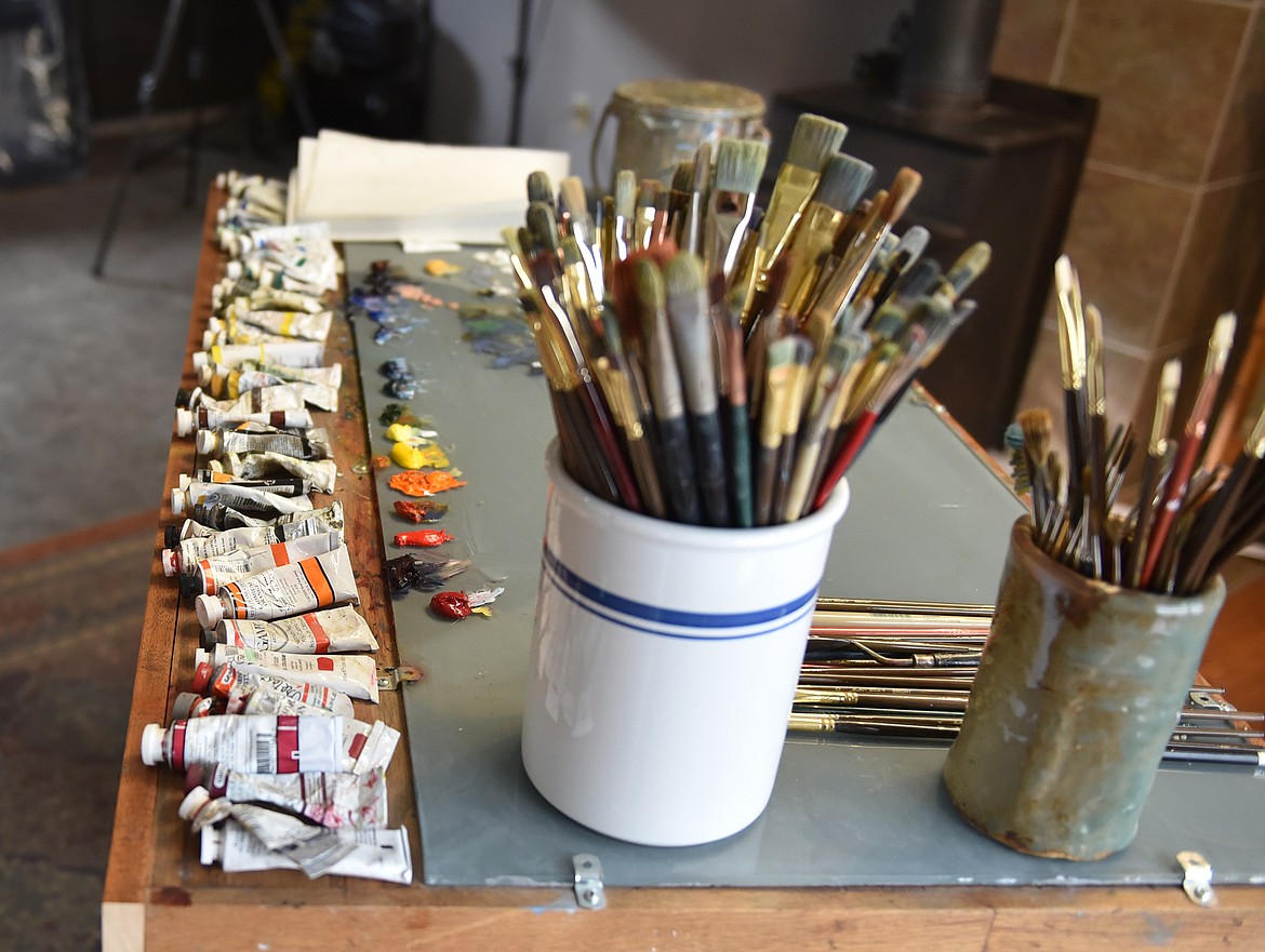 Brushes and paint sit on a work table in Rob Akey’s art studio. (Heidi Desch/Whitefish Pilot)