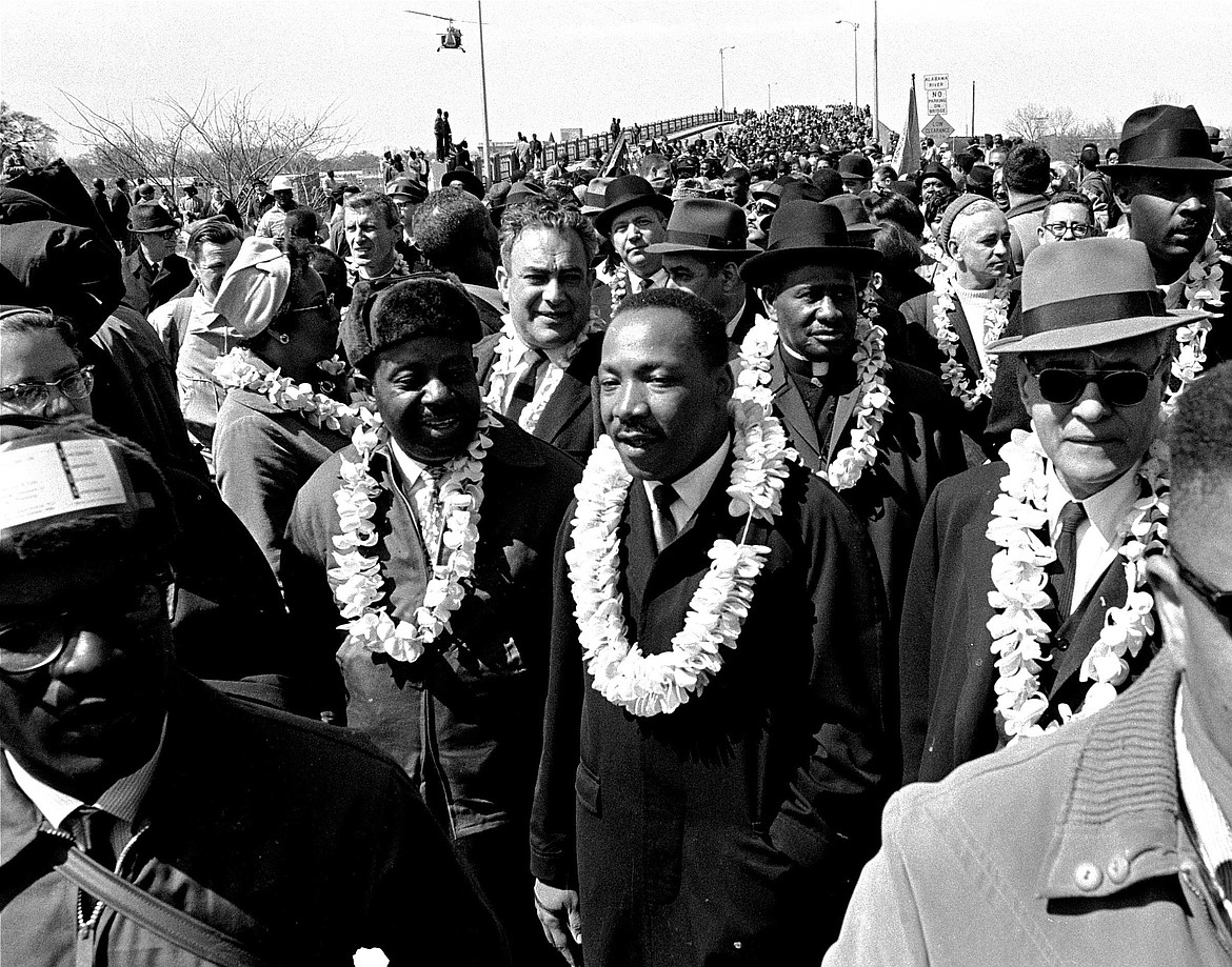 In this March 21, 1965 file photo, Martin Luther King, Jr. and his civil rights marchers cross the Edmund Pettus Bridge in Selma, Ala., heading for the capitol, Montgomery, during a five day, 50 mile walk to protest voting laws. The annual celebration of the Martin Luther King Jr. holiday in his hometown in Atlanta is calling for renewed dedication to nonviolence following a turbulent year. The slain civil rights leader's daughter, the Rev. Bernice King, said in an online church service Monday, Jan. 18, 2021, that physical violence and hateful speech are “out of control” in the aftermath of a divisive election followed by a deadly siege on the U.S. Capitol in Washington by supporters of President Donald Trump.