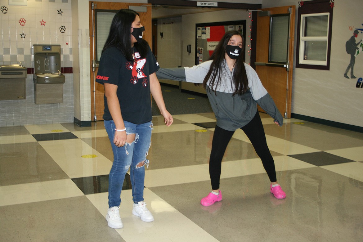 Cindy Magana demonstrates a new fact of life at Othello High School - if you're close enough to touch somebody, in this case Loryn Maples (left), you're too close. The school's ASB officers were asked to film a video detailing the new rules in advance of the high school's reopening Jan. 25.