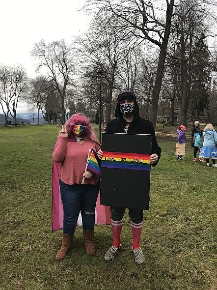 Kaci Thomas is draped in a lesbian flag and Craig Thom holds a sign that reads 'Love is Love.'