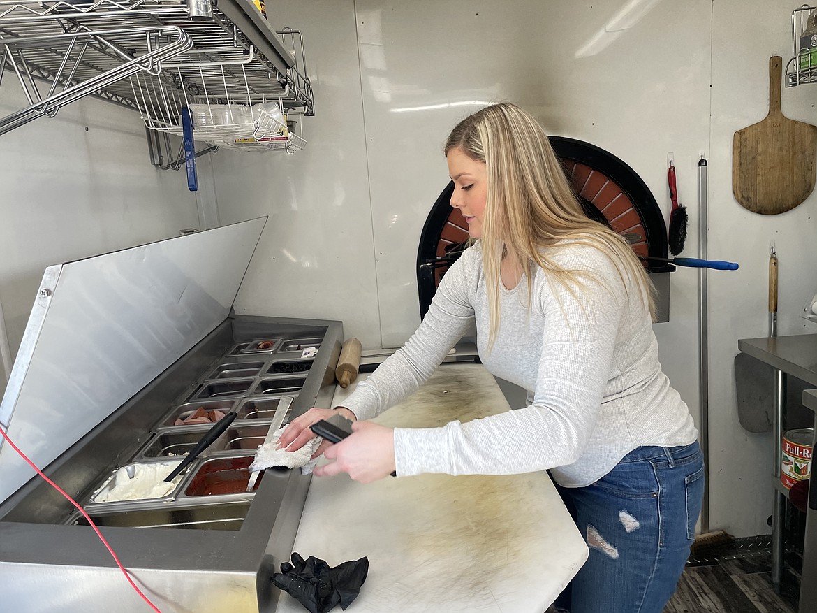 Nakia Reynolds cleans up after a long lunch rush last week inside the Gosi Artisan Woodfire pizza trailer. Reynolds described the workspace as very small, noting "It’s great for one person is working in here."