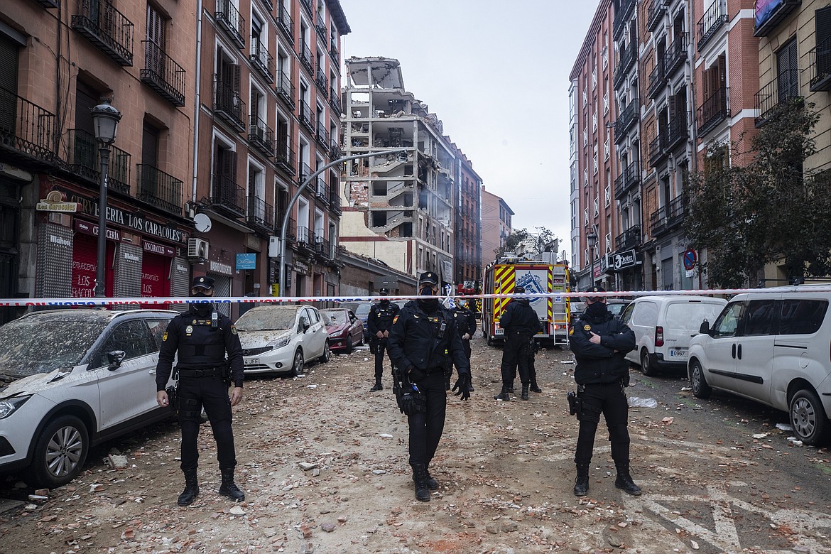 Police officers cordon off Toledo Street following an explosion in downtown Madrid, Spain, Wednesday, Jan. 20, 2021. A loud explosion has partially destroyed a small building flanked by a school and a nursing home in the center of Spain's capital.